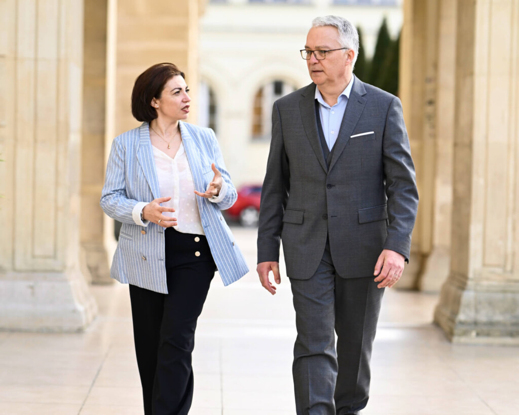 Isolina BOUDI et Lionel GUÉRIN, consultants en recrutement chez Learn2Fly RH, échangent en marchant sous une colonnade lors d'un accompagnement personnalisé de candidat.